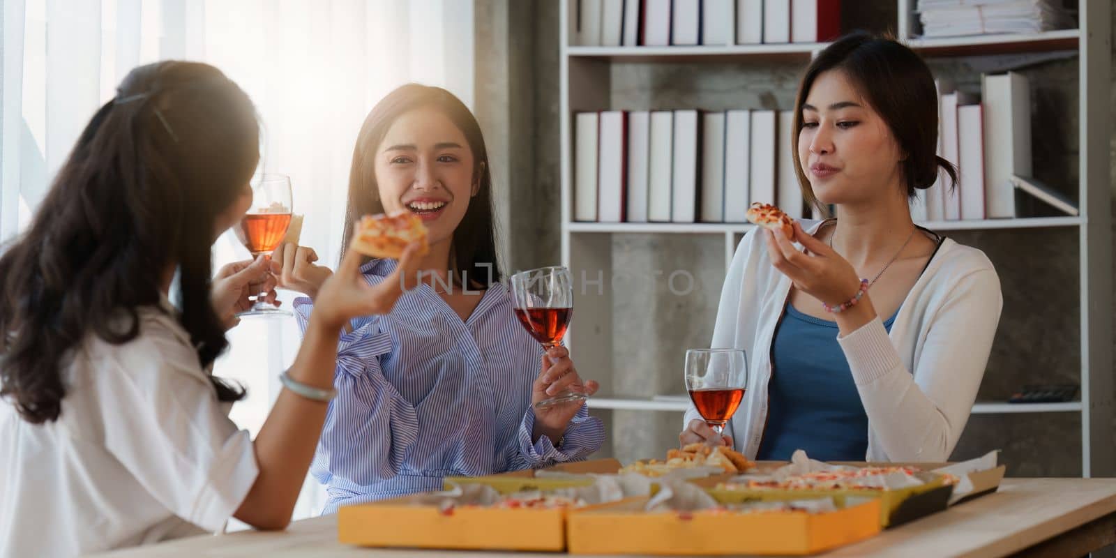 Friends at birthday party clinking glasses with champagne and pizza, enjoying Christmas vacation, pizza on the table. Holiday Party event.