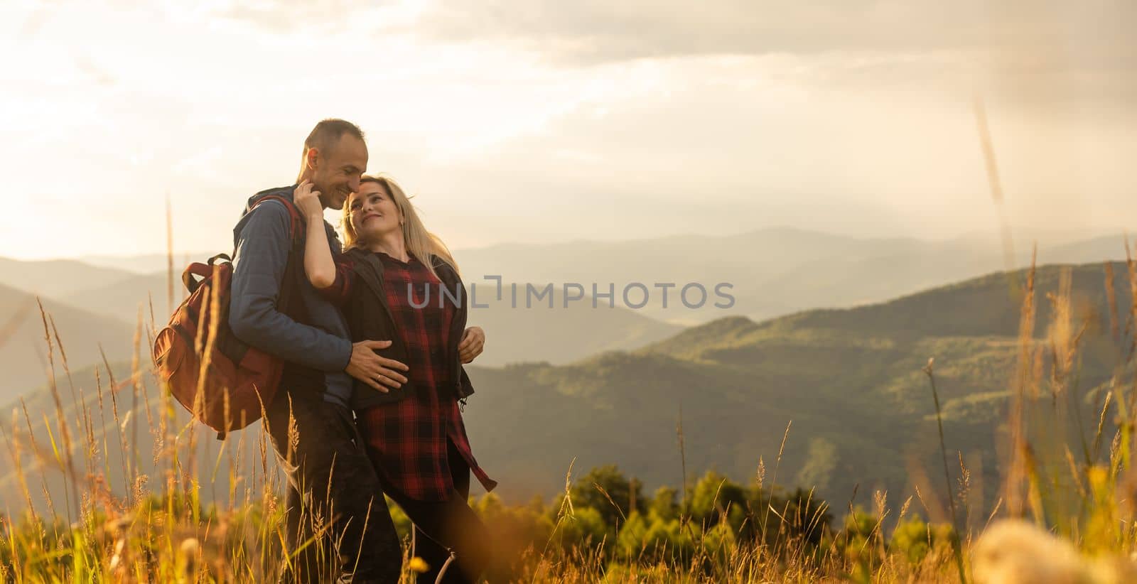 travel, tourism and people concept - happy couple with backpacks having fun over mountains background by Andelov13