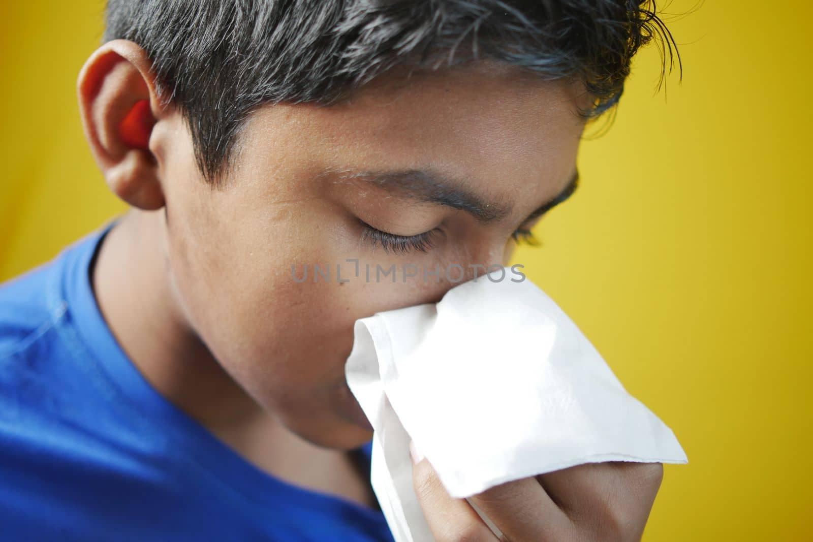 Sick boy with flu blow nose with napkin