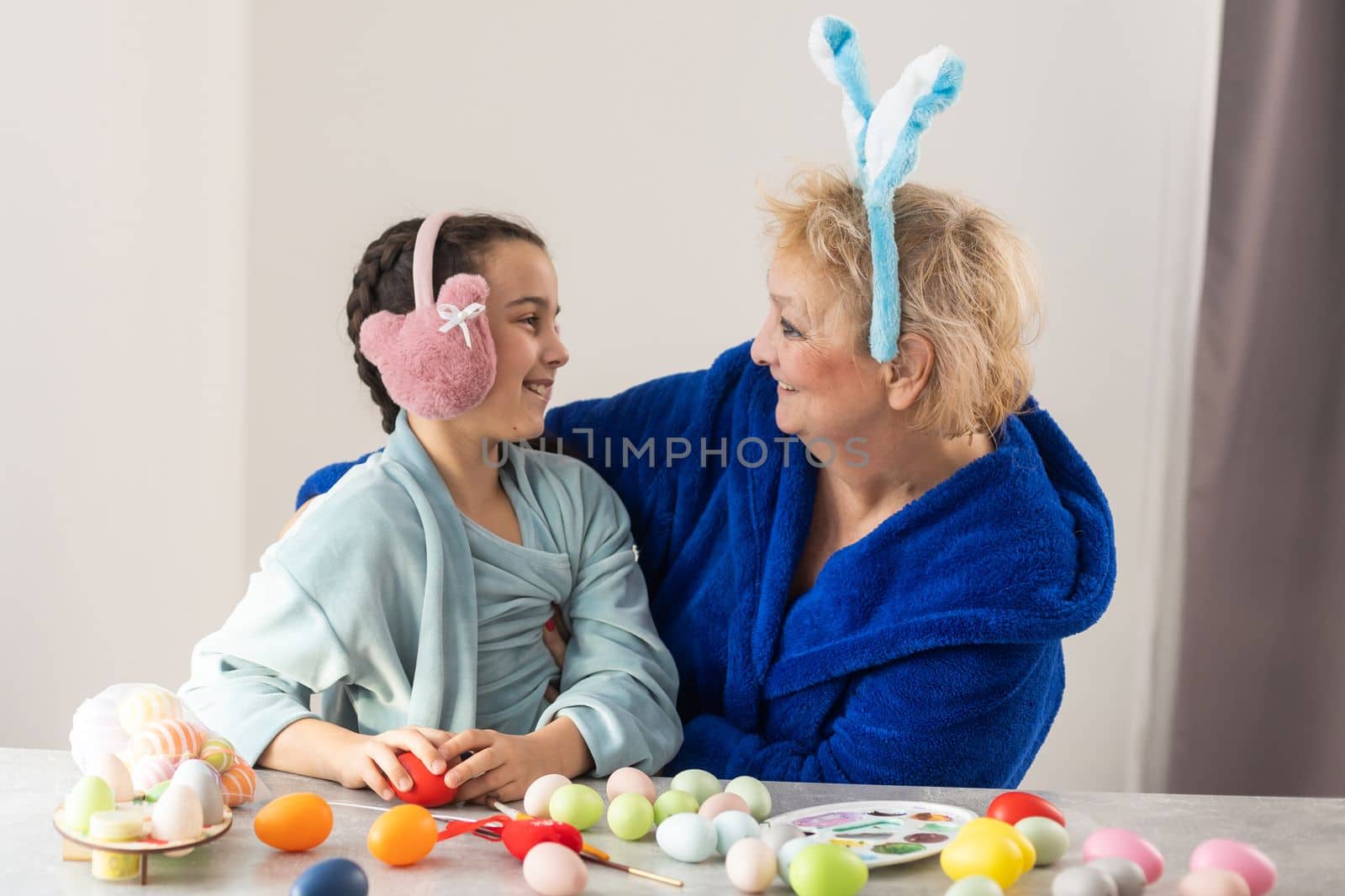 Grandmother painting eggs with granddaughter.