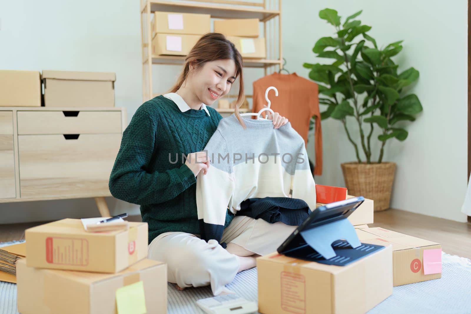 Starting small business entrepreneur of independent young Asian woman online seller using a tablet computer showing products to a customer before making a purchase decision. SME delivery concept.