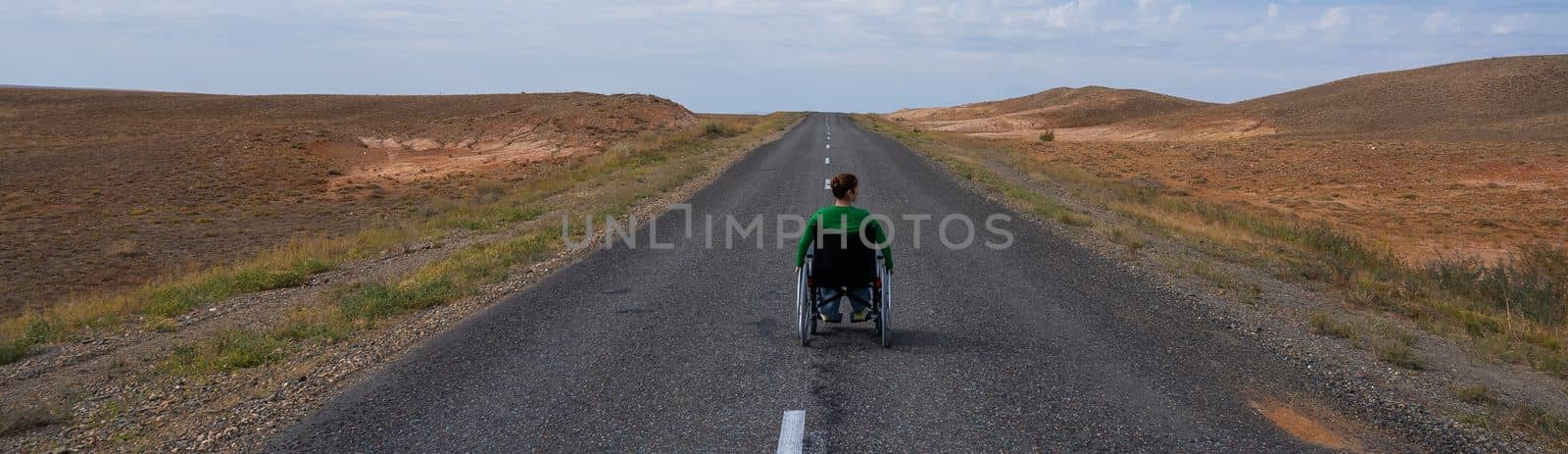 Woman in a wheelchair on a highway in the steppes. by mrwed54