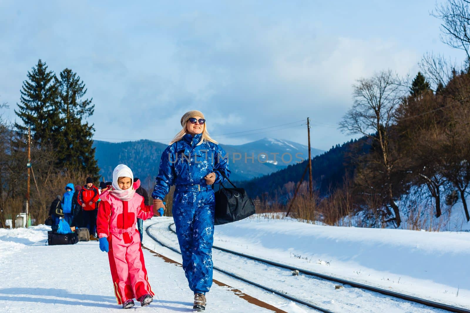 mother and daughter are wearing ski suits near the railway