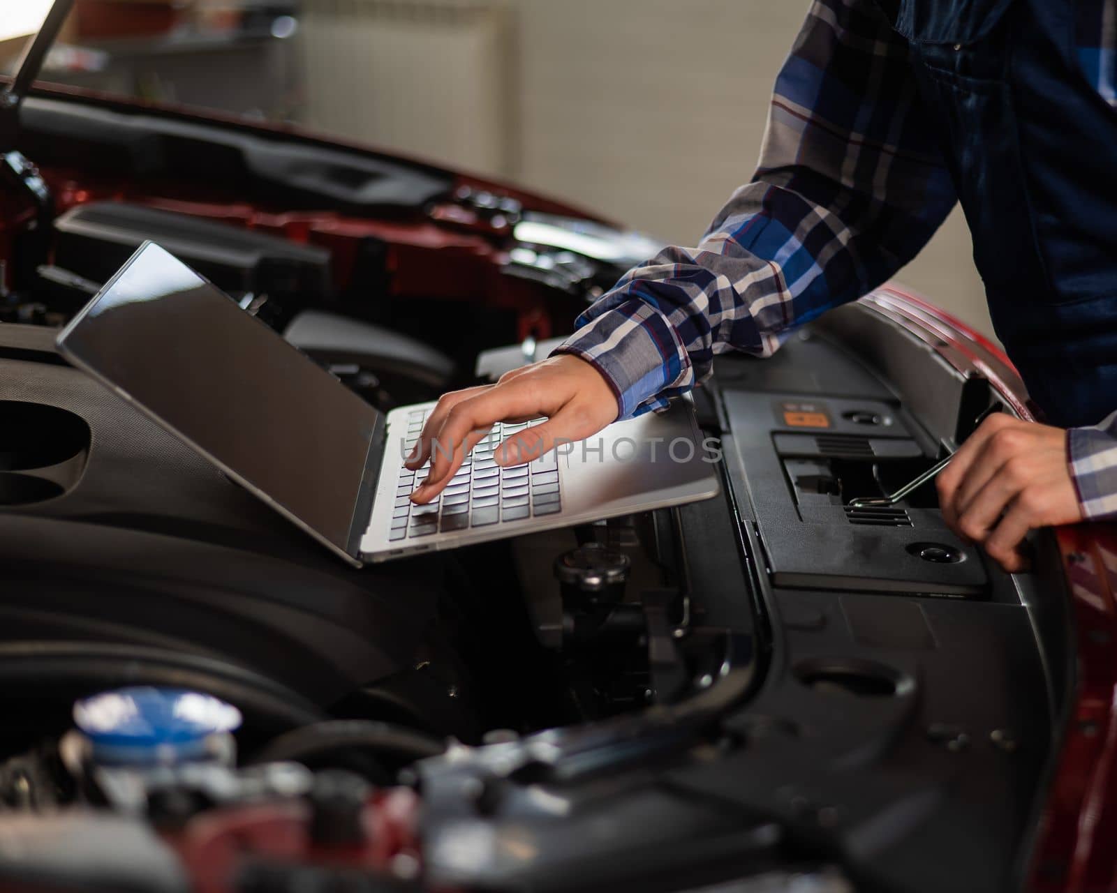 Woman auto mechanic doing engine diagnostics using laptop
