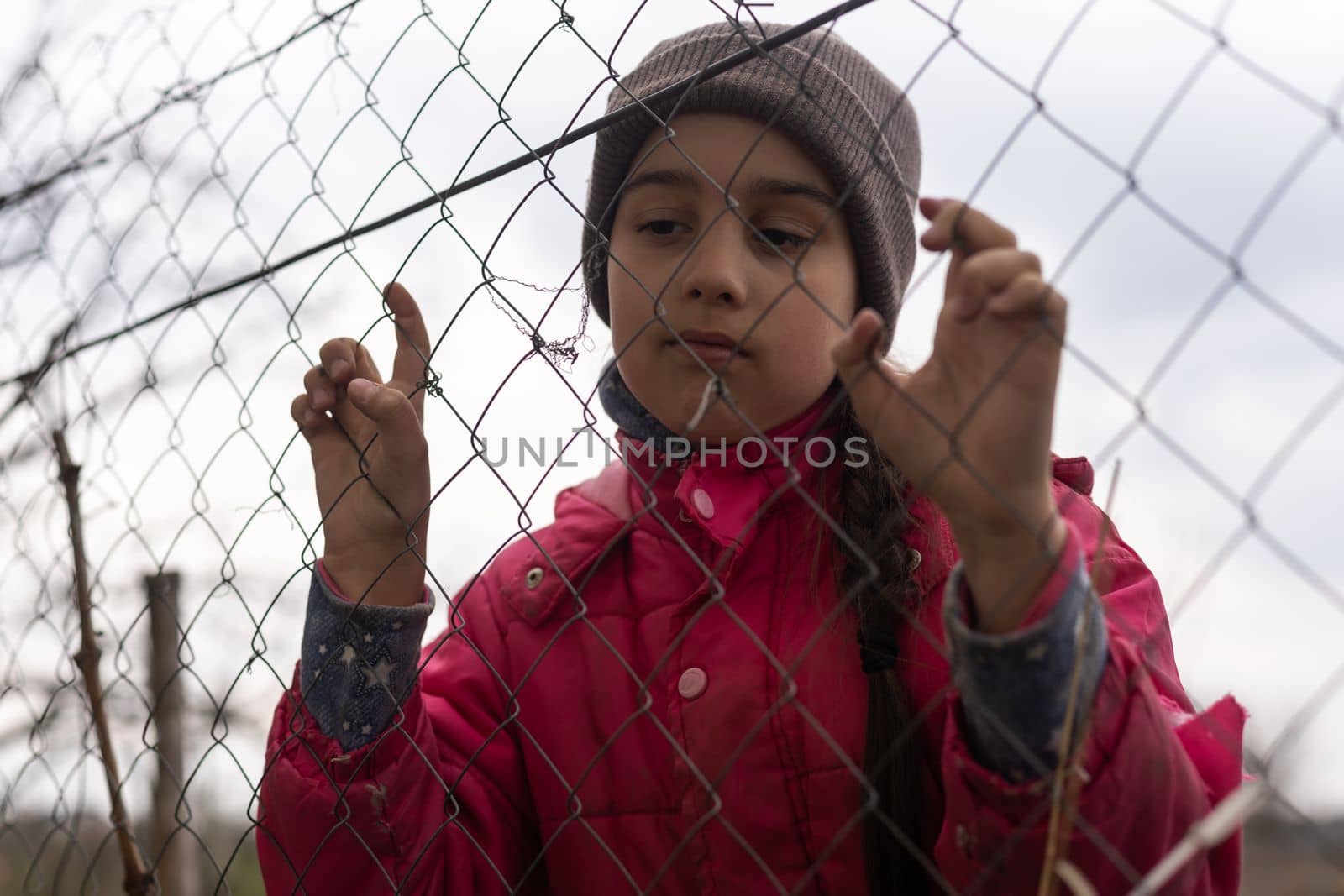 Photo of a little girl holding bars. Sad little girl behind iron bars. Little girl behind the bars. Violence concept