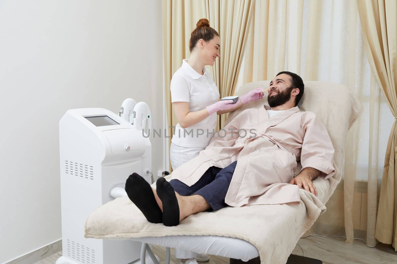 Bearded man getting laser facial treatment by professional cosmetologist in a beauty clinic by Mariakray