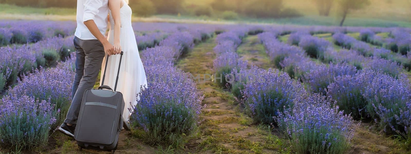 Smiling young couple embracing at the lavender field, holding hands, walking. by Andelov13