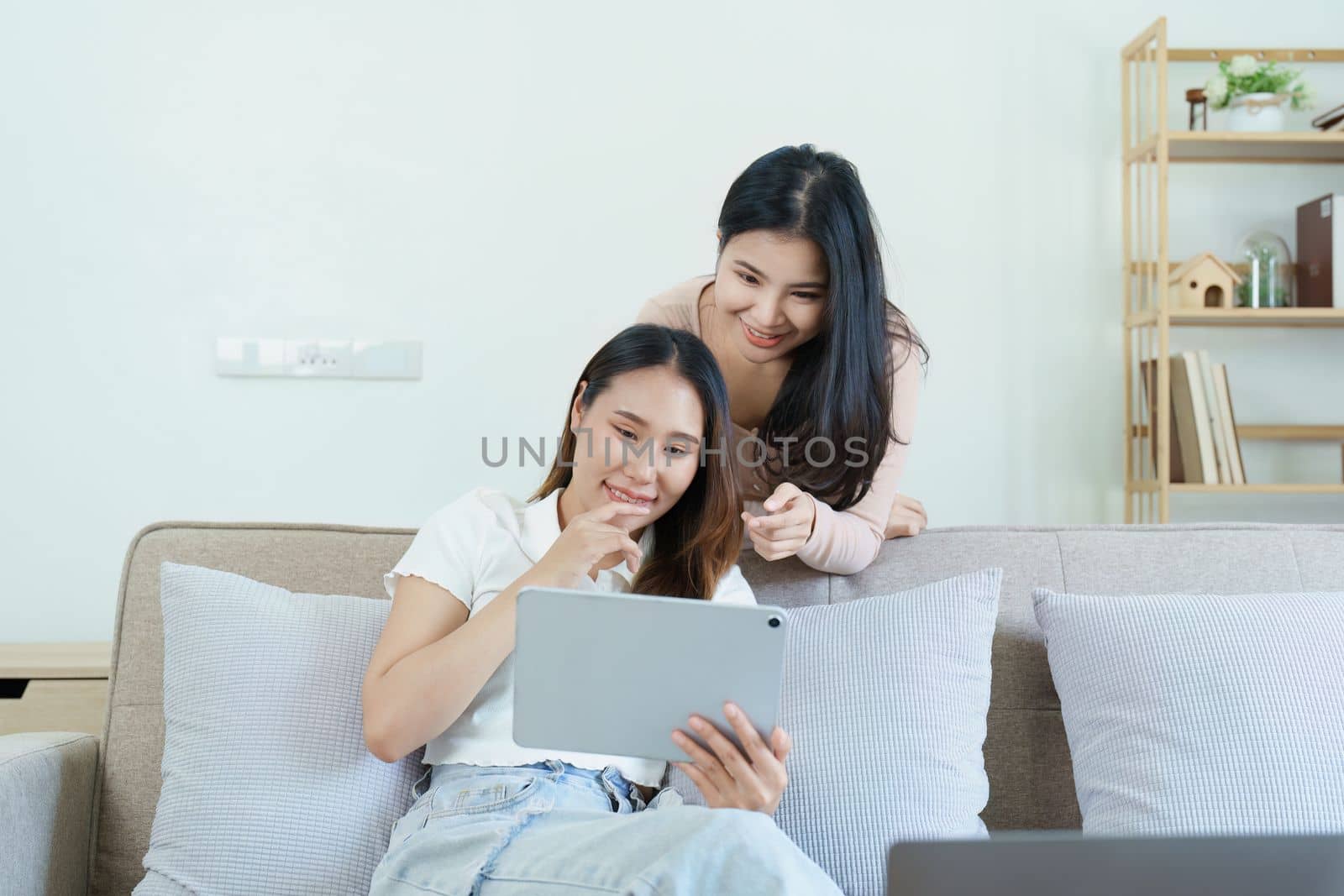 lgbtq, lgbt concept, homosexuality, portrait of two asian women posing happy together and loving each other while playing tablet at sofa.