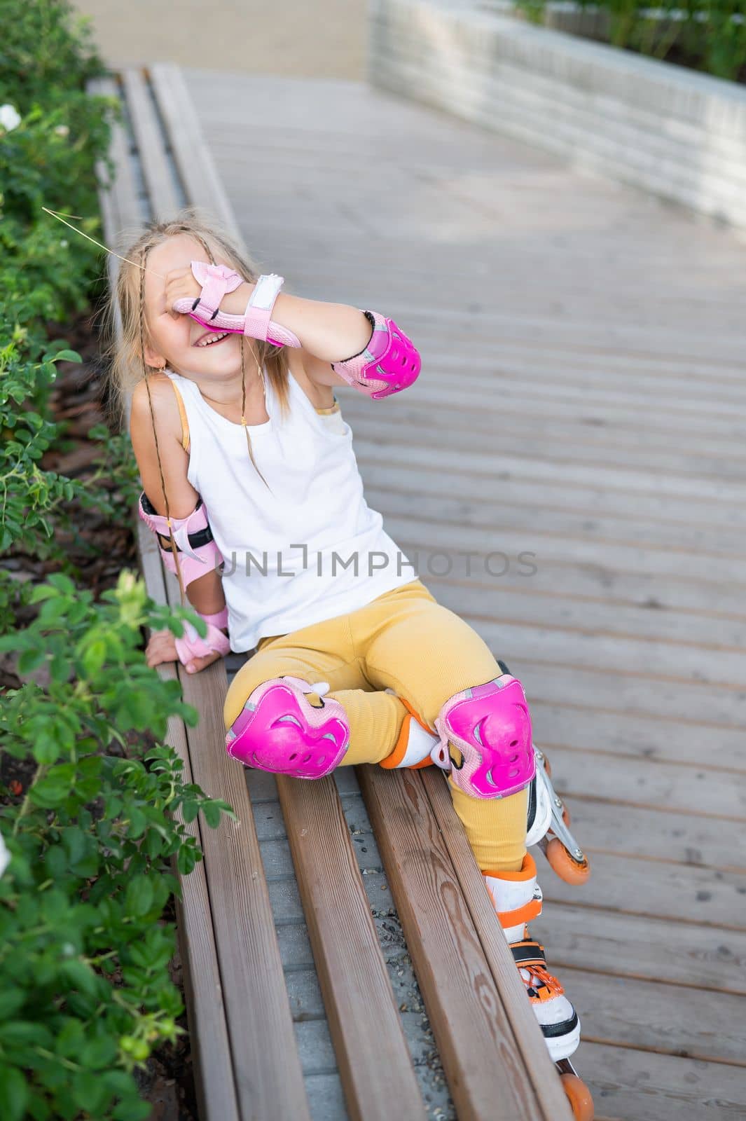 A little Caucasian girl in roller skates sits on a bench. by mrwed54