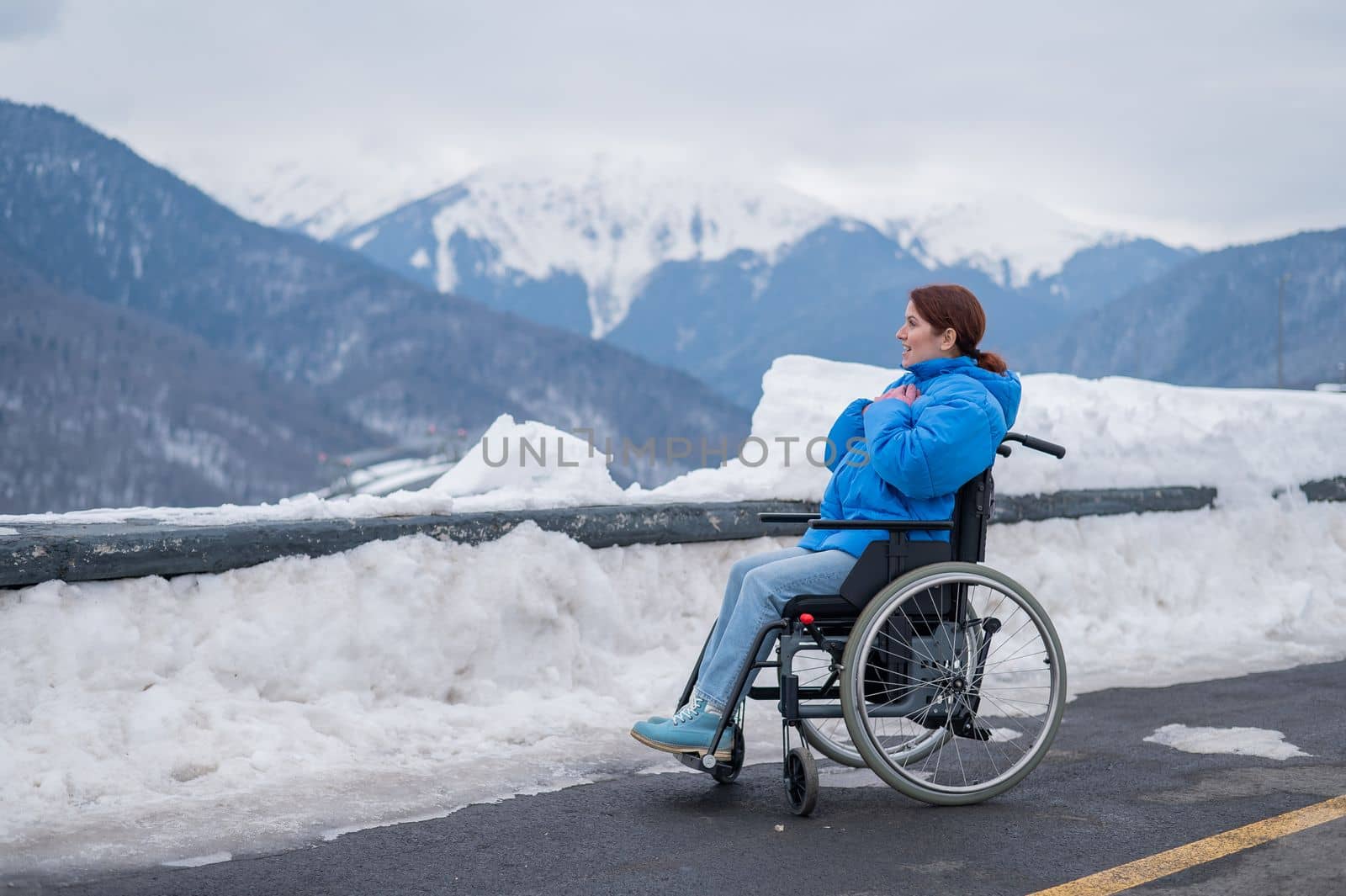 Caucasian woman in a wheelchair travels in the mountains in winter