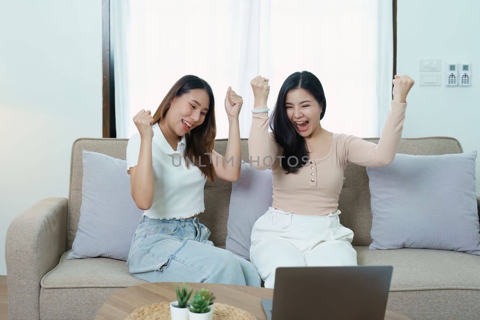 lgbtq, lgbt concept, homosexuality, portrait of two asian women posing happy together and loving each other while playing computer laptop on sofa by Manastrong