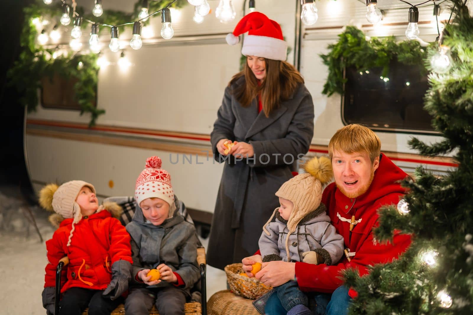 Happy Caucasian family celebrating Christmas outdoors. Parents and three sons travel in a camper