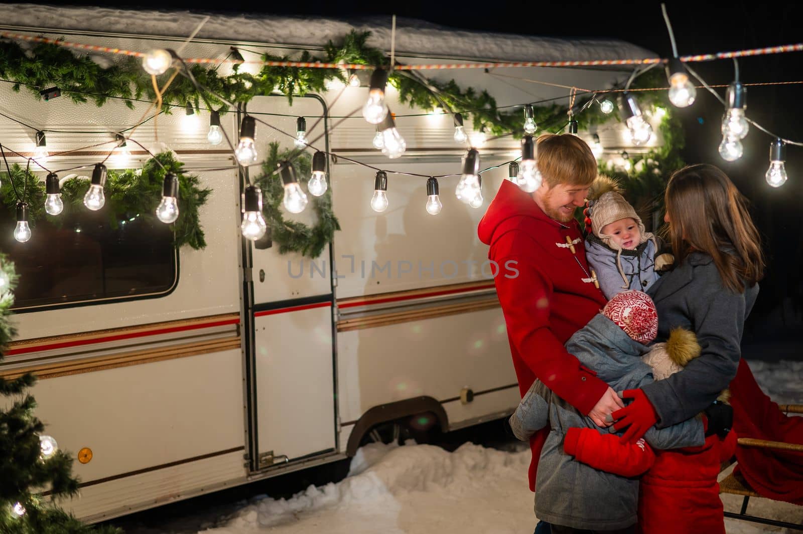 Happy caucasian family hugging outdoors. Christmas decorations. Parents and three sons travel in a camper