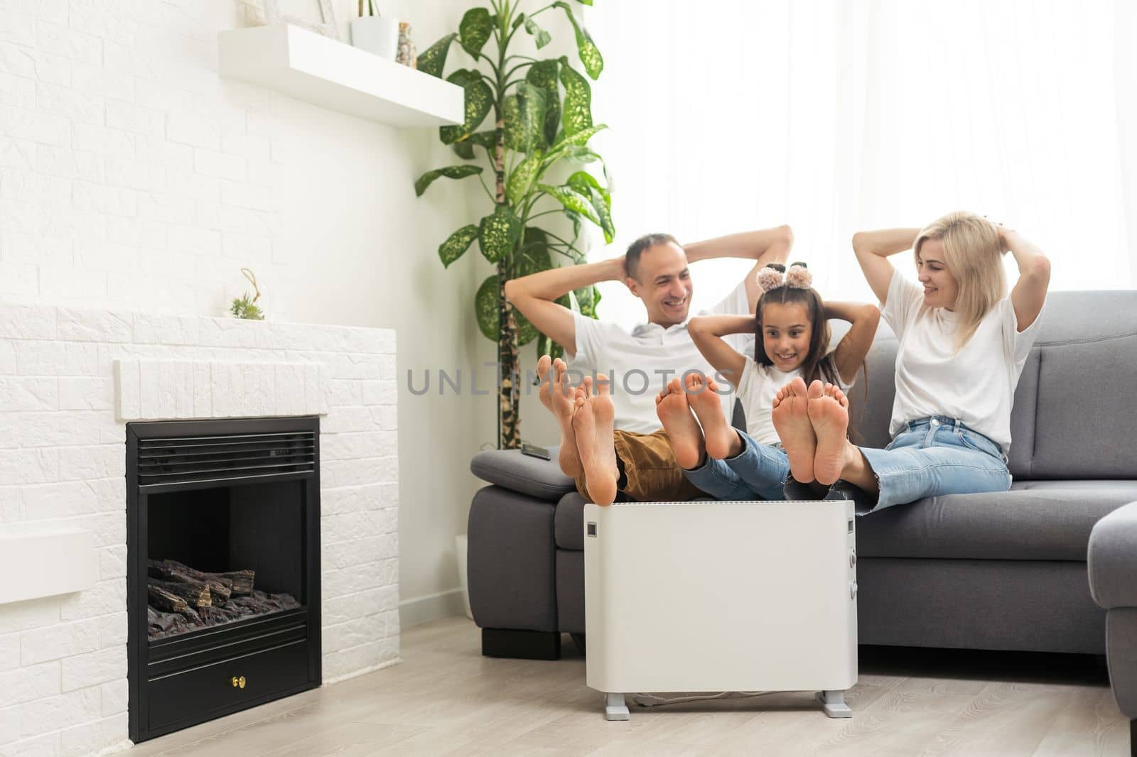 Family warming up near home heater at winter cold time. The symbolic image of the heating season at home. by Andelov13