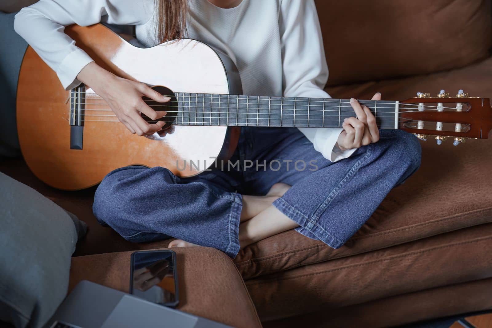 Portrait of young asian woman playing guitar on sofa relaxing stress on vacation.