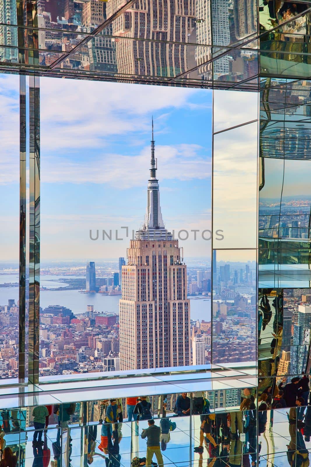 Image of Detail top of Empire State Building from high up Summit One inside mirror glass reflection room full of tourists