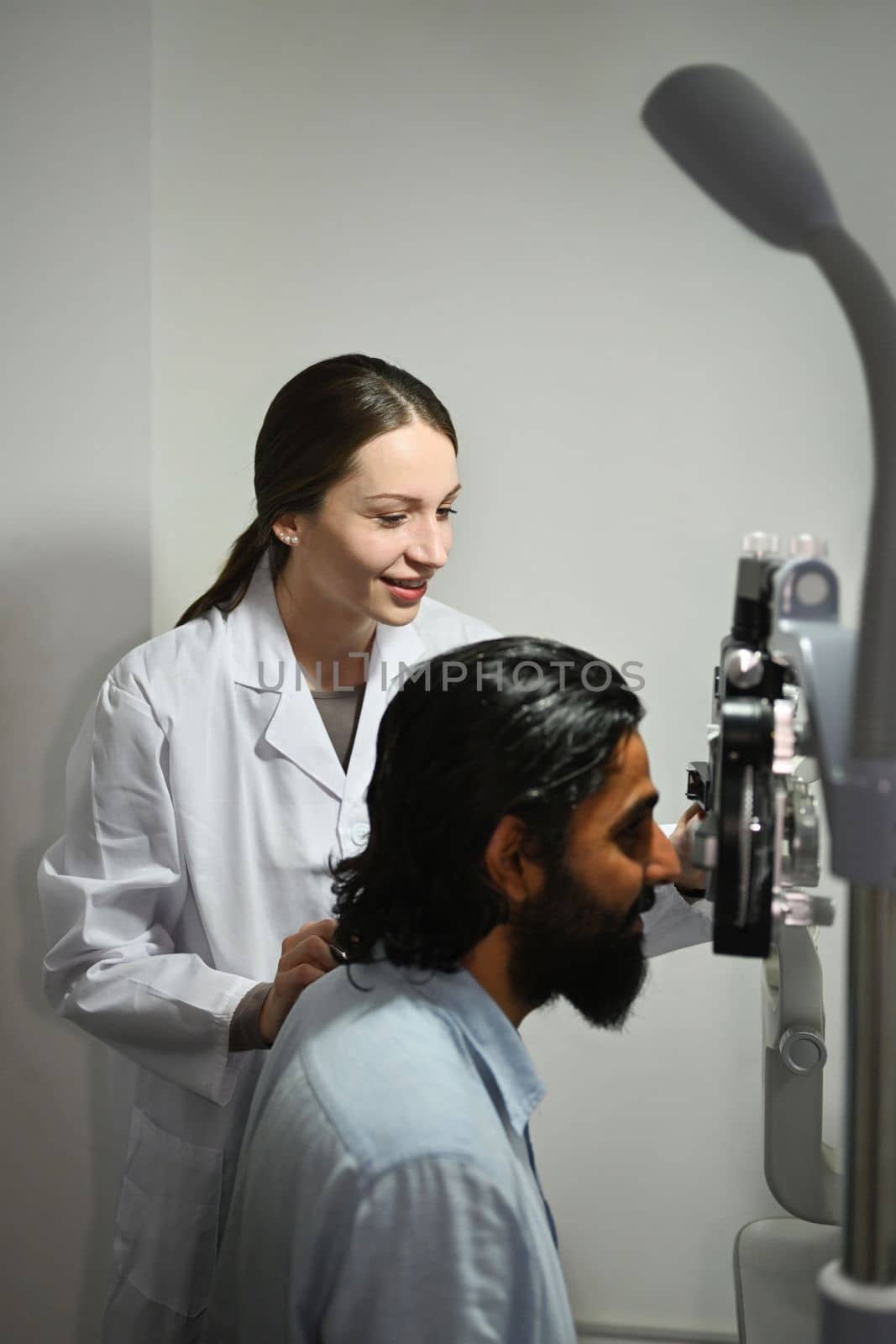 Young Indian man checking eyesight on auto refractor in ophthalmologist clinic. Eye health check and ophthalmology concept by prathanchorruangsak