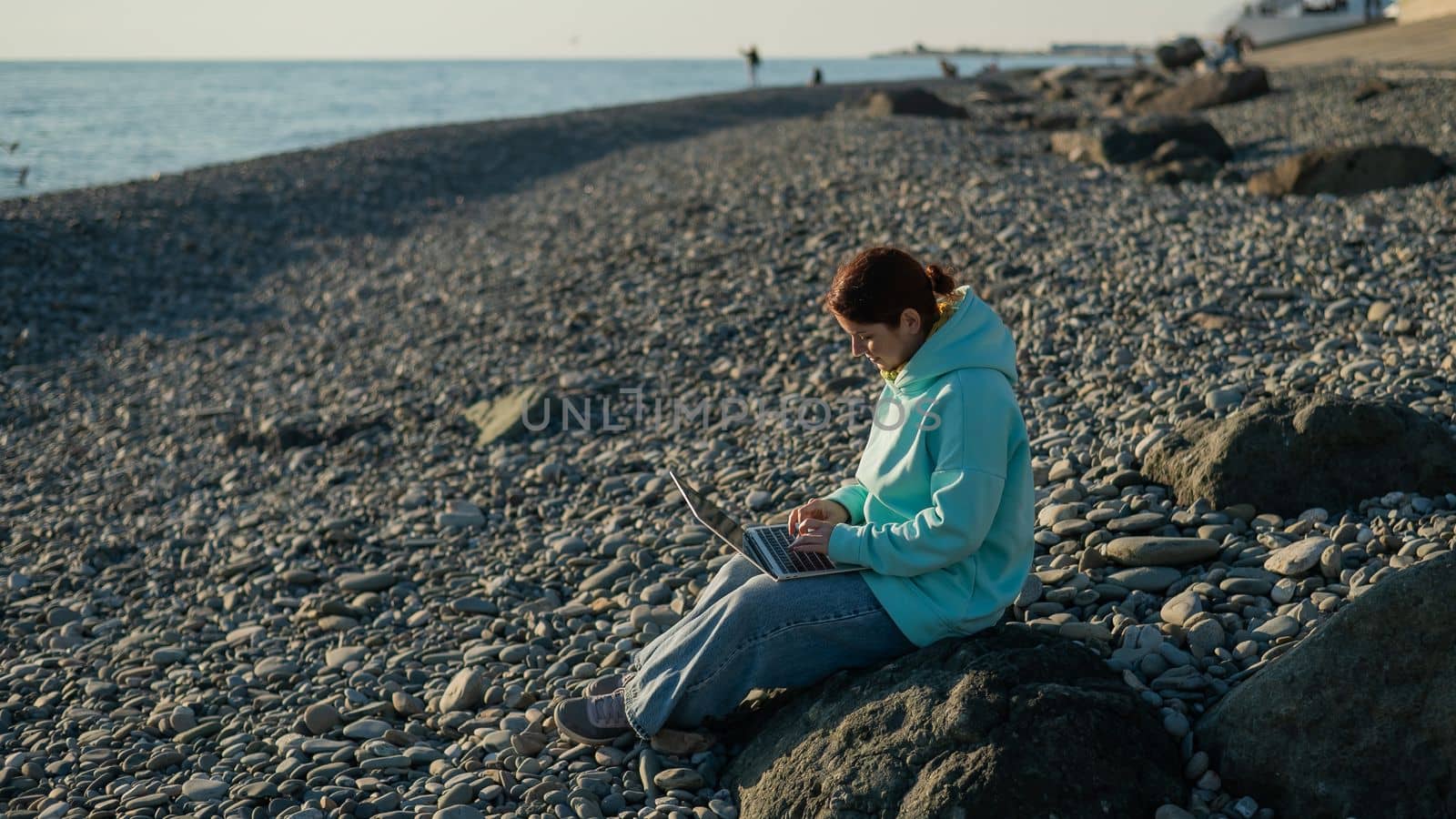 Caucasian woman working freelance on laptop on the beach