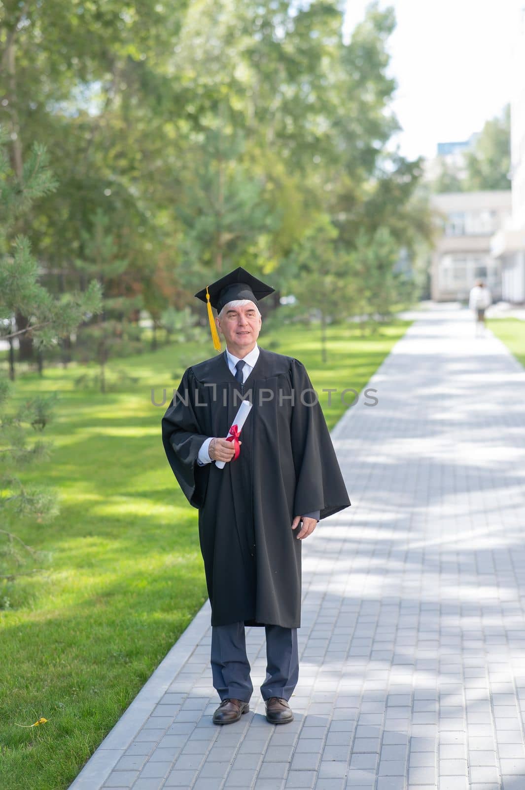 An old man in a graduation gown walks outdoors and holds a diploma. by mrwed54