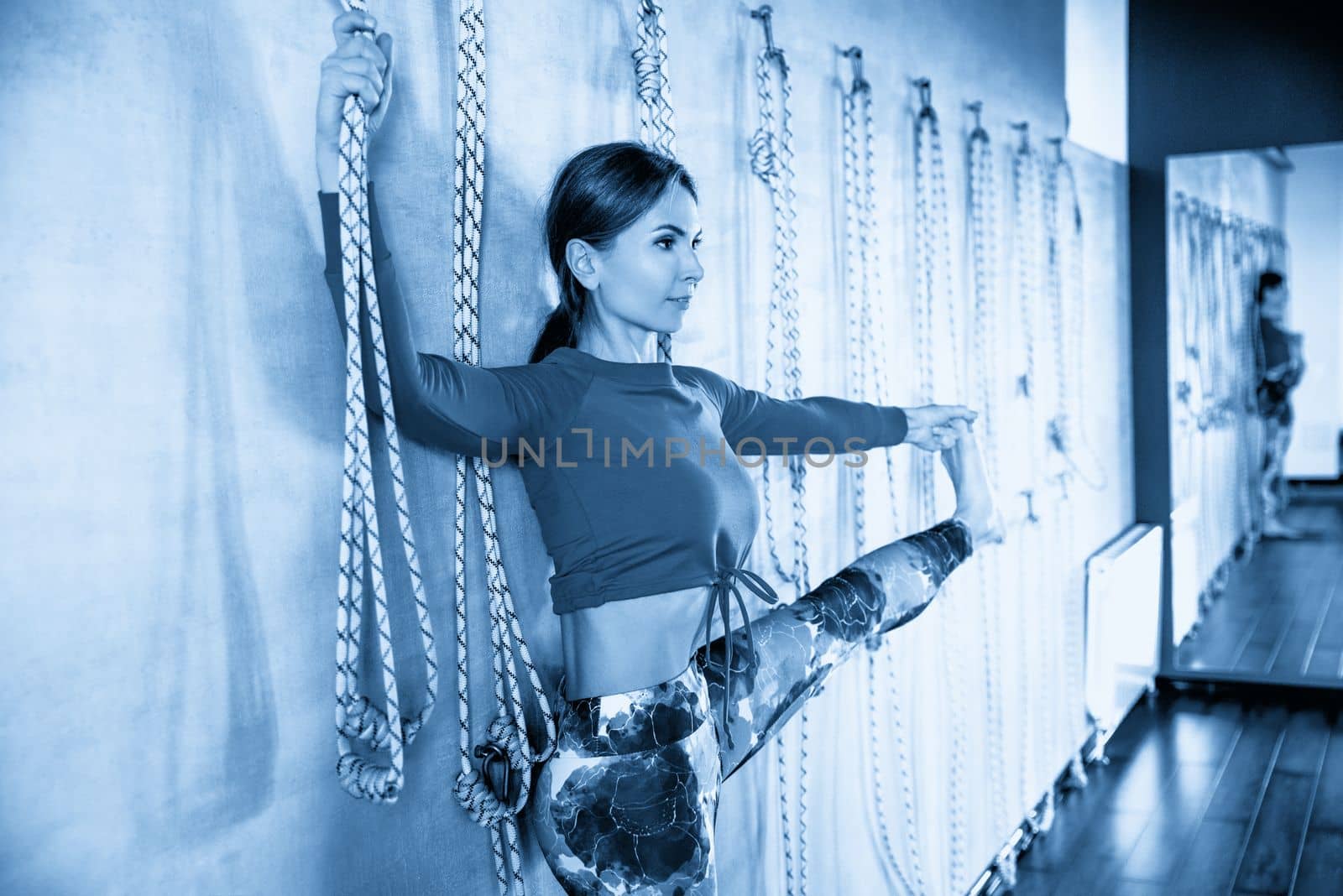 Young girl doing yoga pose with rope against a wall
