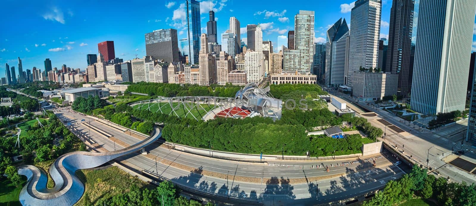 View over Millennium Park with walking bridge and theater in downtown Chicago lined with skyscrapers by njproductions