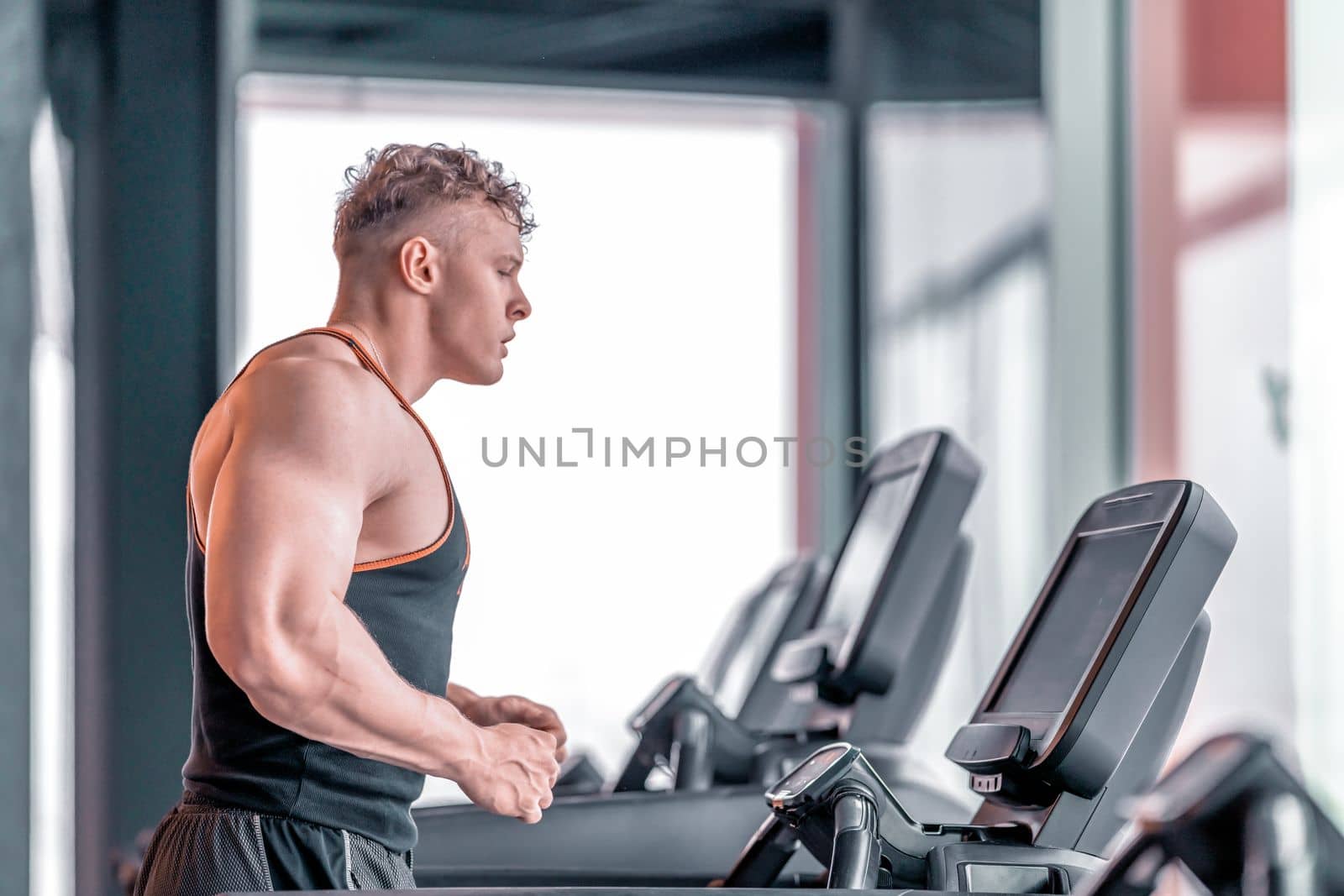 young athlete runs on a treadmill in the gym by Edophoto