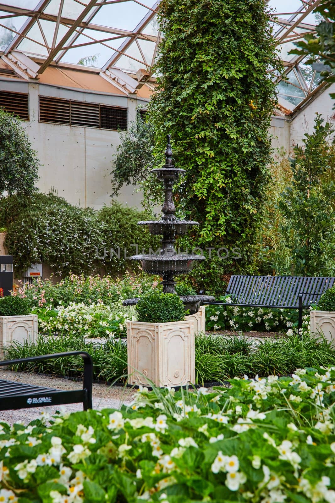 Image of Detail of black water fountain inside botanical gardens with benches