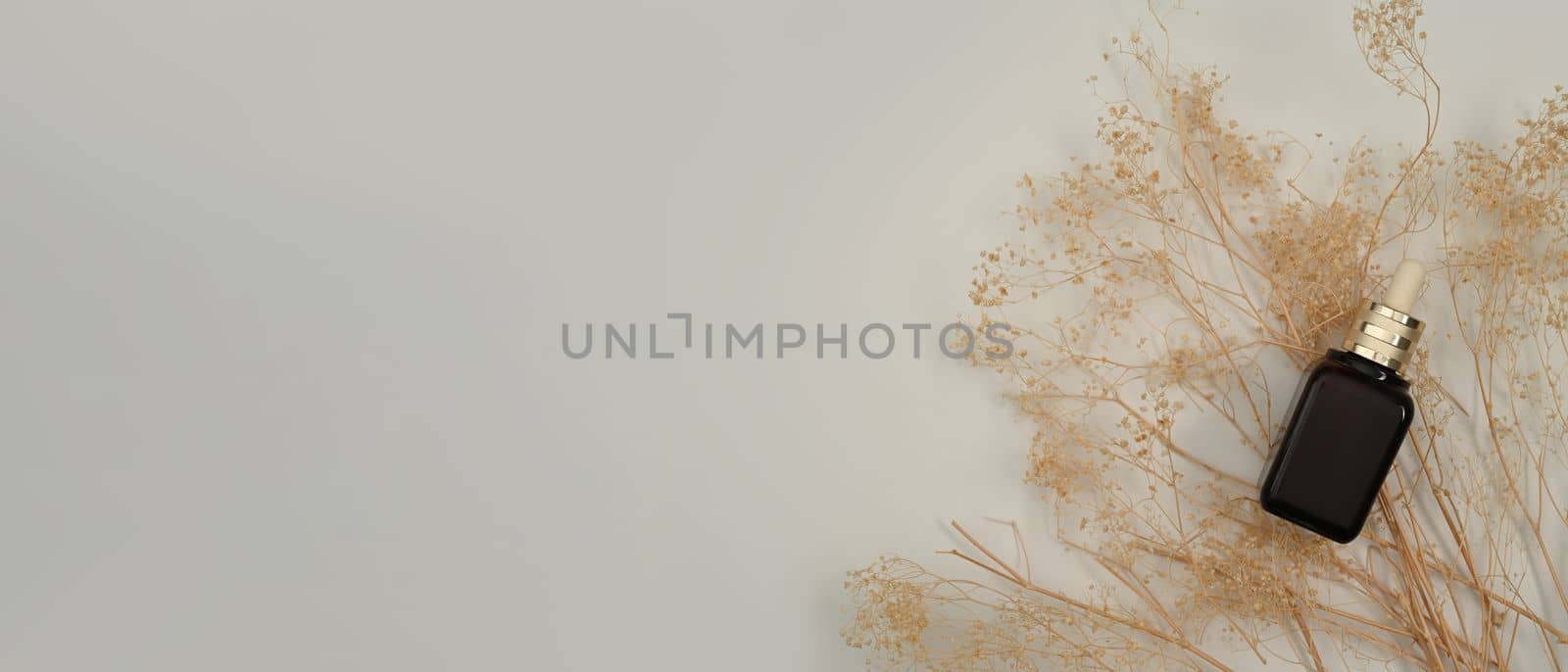 Realistic dropper bottle with dried flowers on white background with copy space for your advertise text.