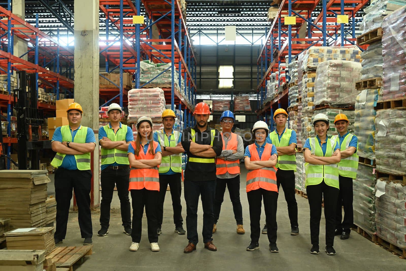 Group of warehouse worker standing in line with arms crossed together at logistic distribution warehouse. Corporate team concept.