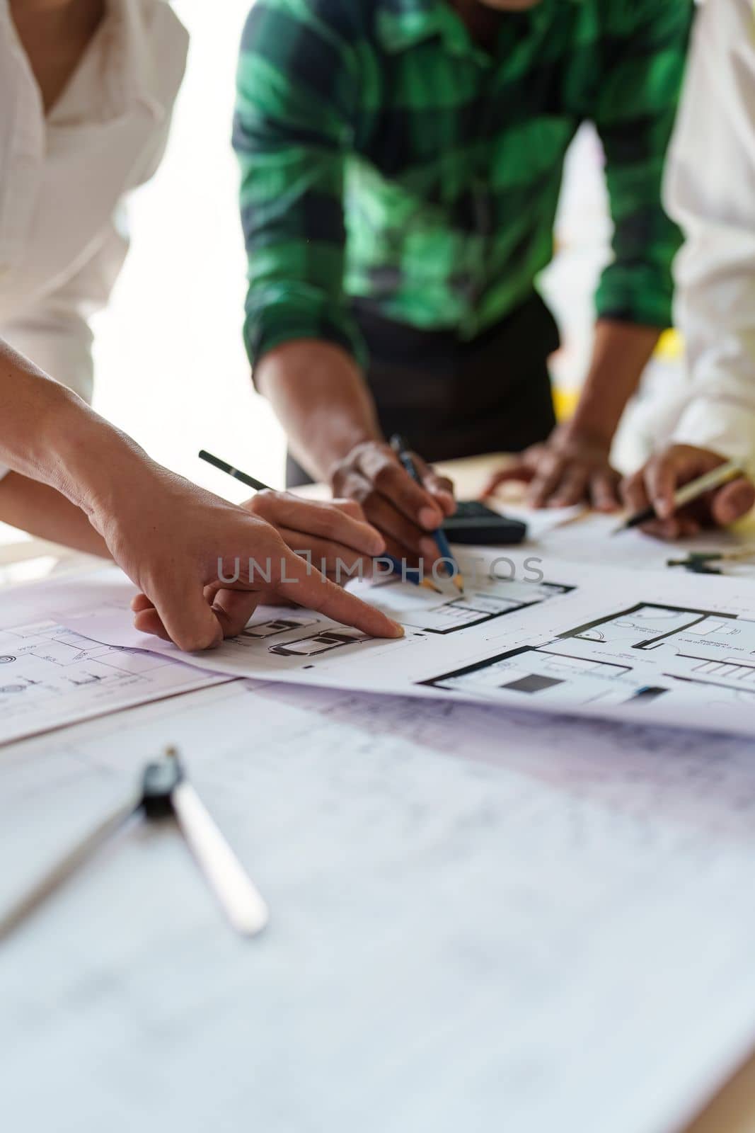 Architect team working with blueprints for architectural plan, engineer sketching a construction project, green energy concept.