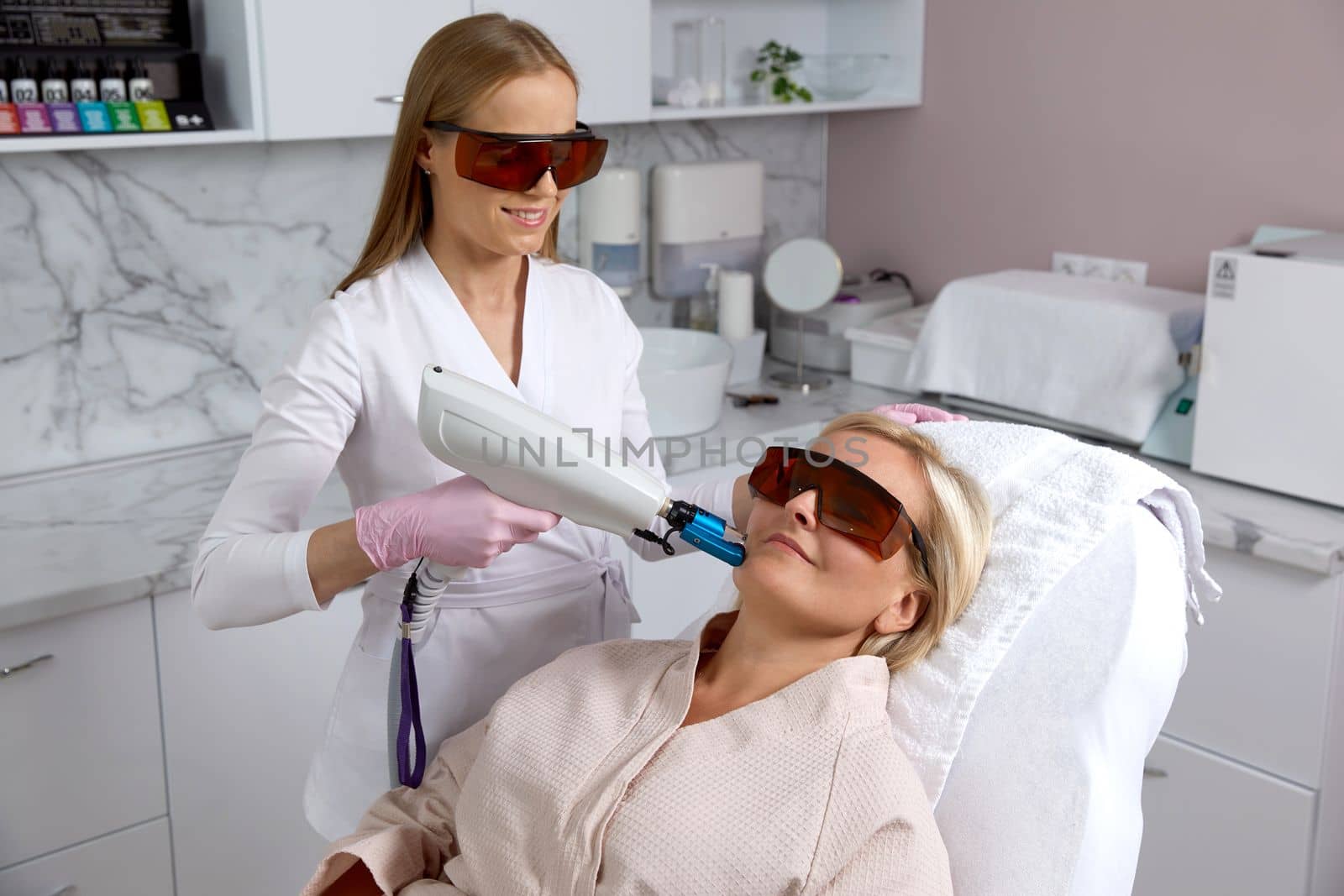 Woman receiving laser treatment in cosmetology clinic by Mariakray