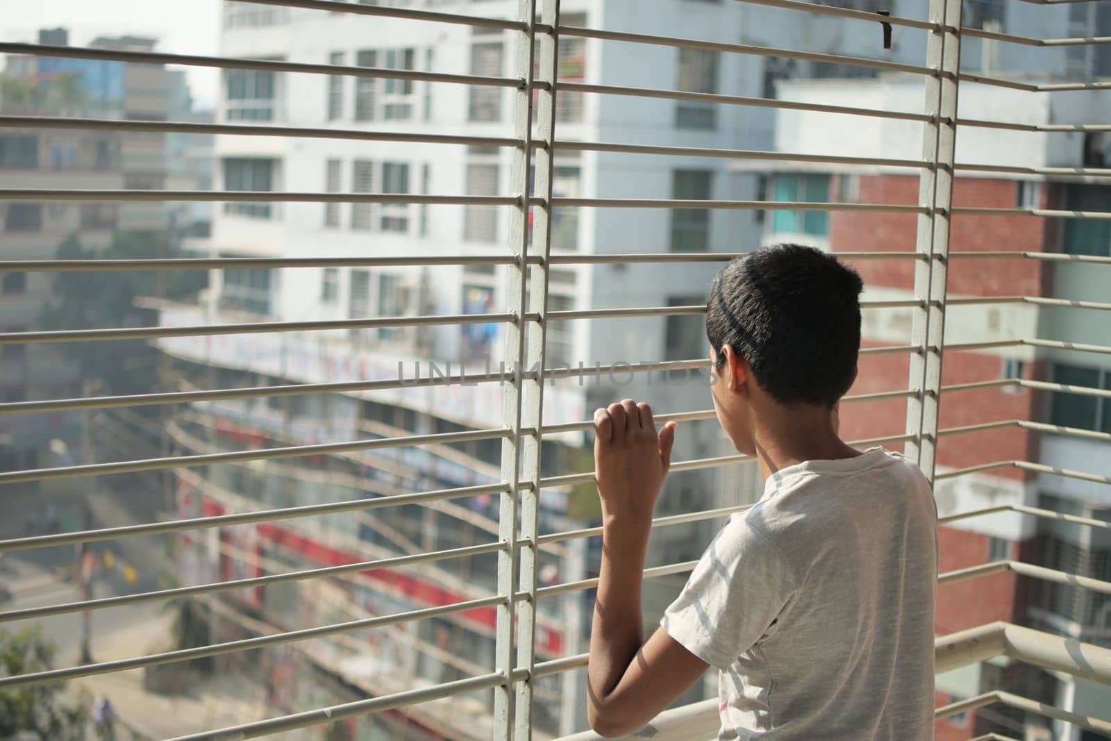 sad teenage boy looking through window .