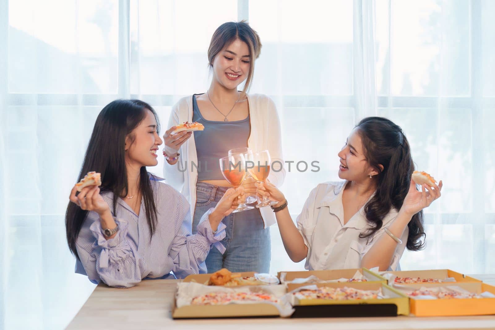 Friends at birthday party clinking glasses with champagne and pizza, enjoying Christmas vacation, pizza on the table. Holiday Party event.