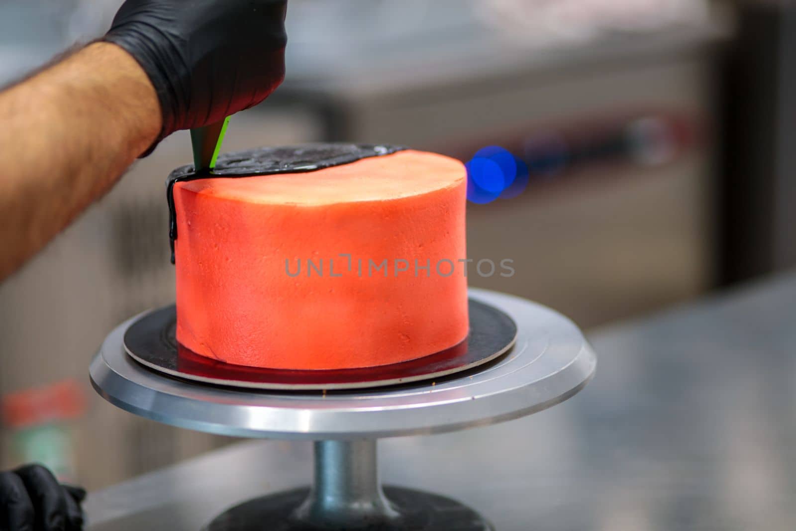 topping a red cake with black dark chocolate icing
