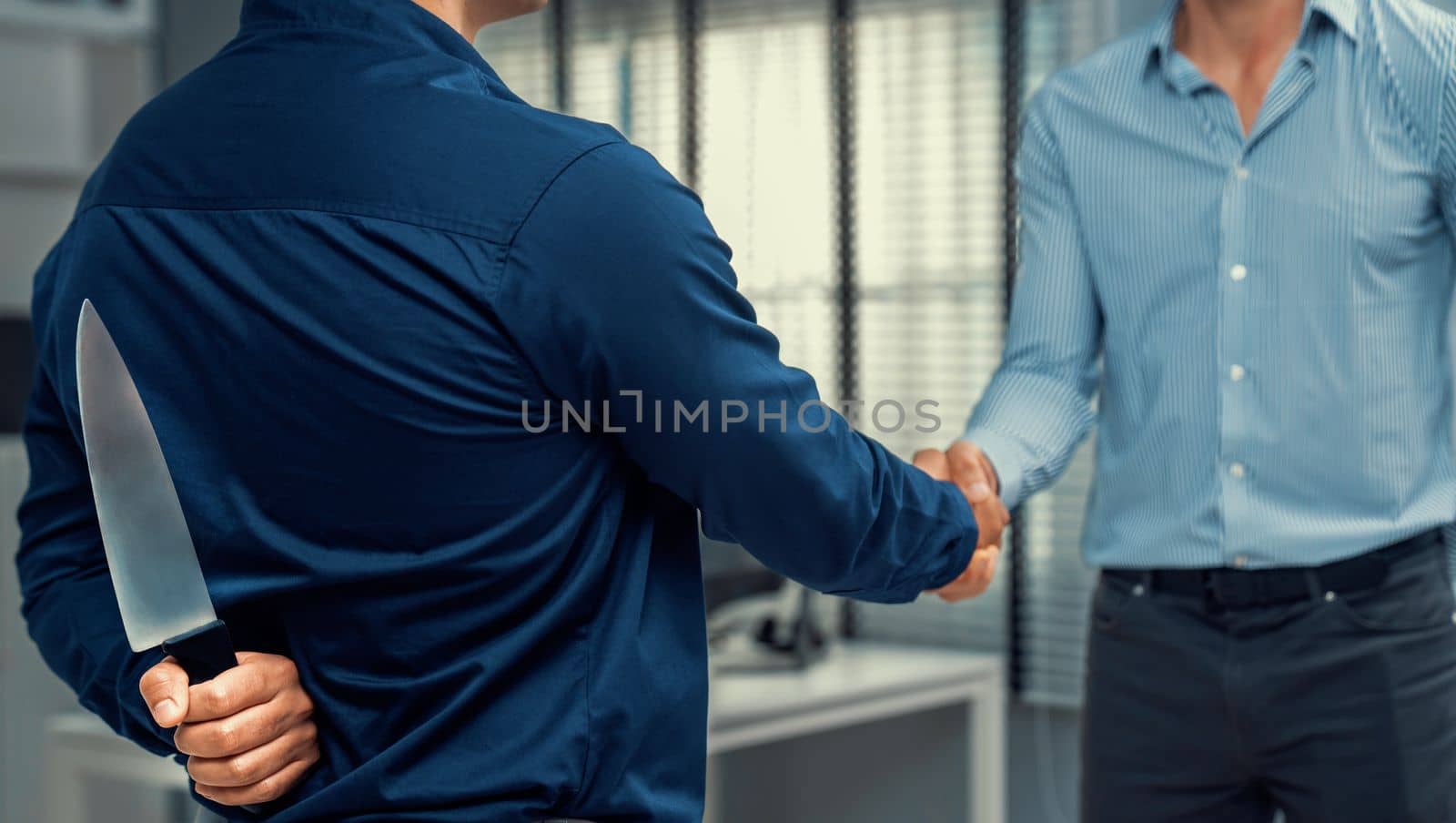 Back view of businessman shaking hands with another businessman while holding a knife behind his back. Concept of back backstabbing in business, backstabbing between colleagues.