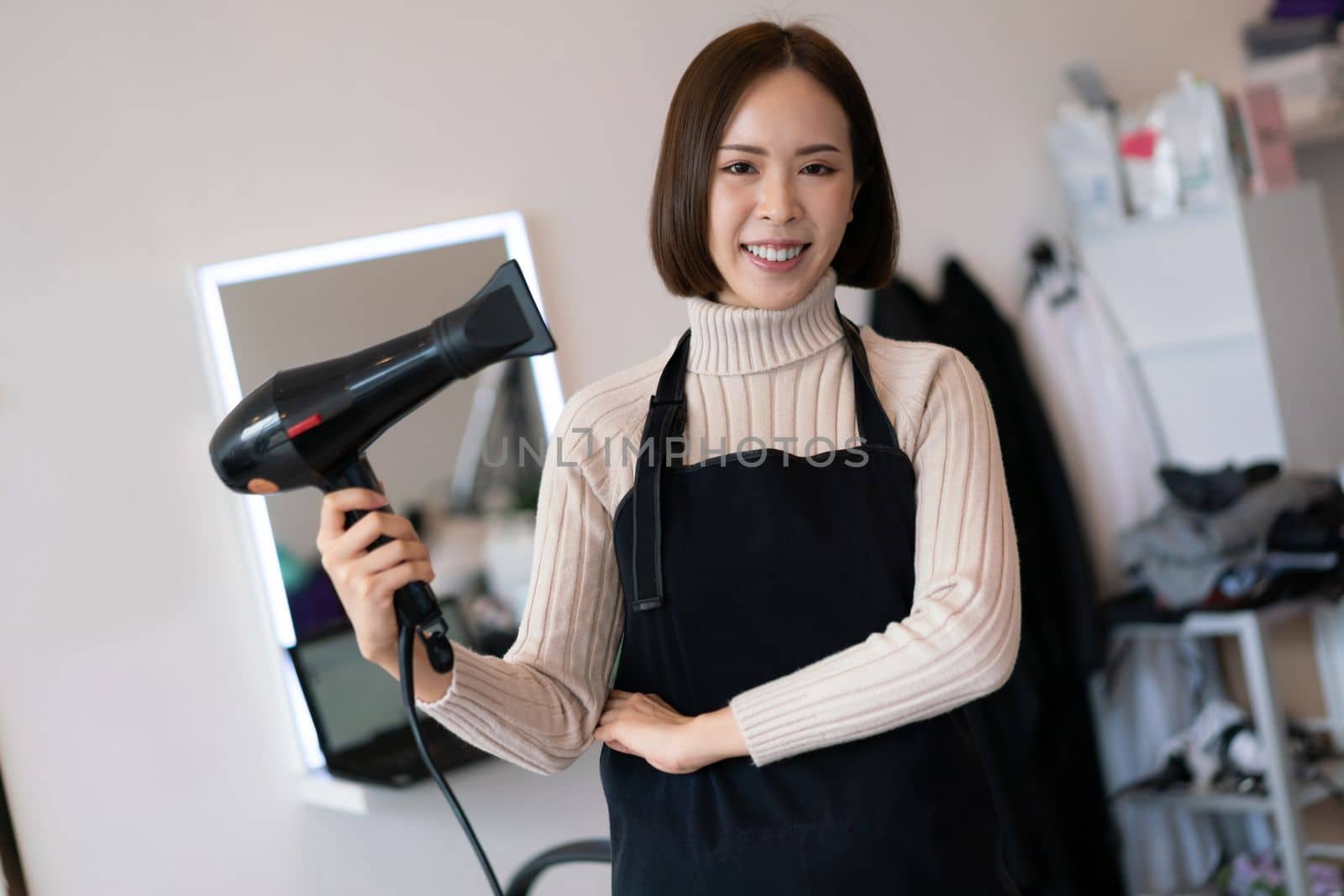 Portrait of a young asian female hairdresser holding qualified haircut tools. by biancoblue