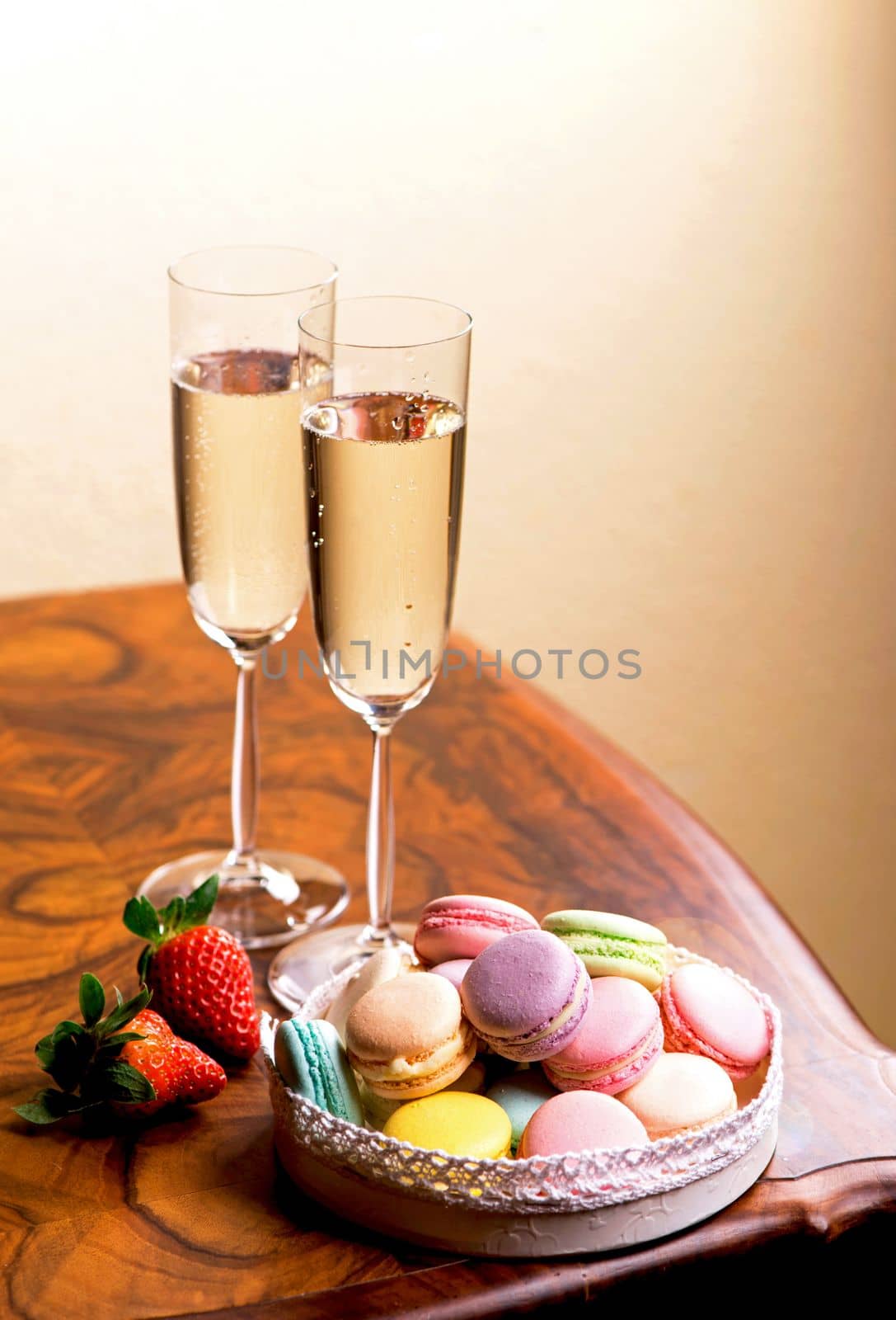 champagne and macarons with strawberries on a wooden table