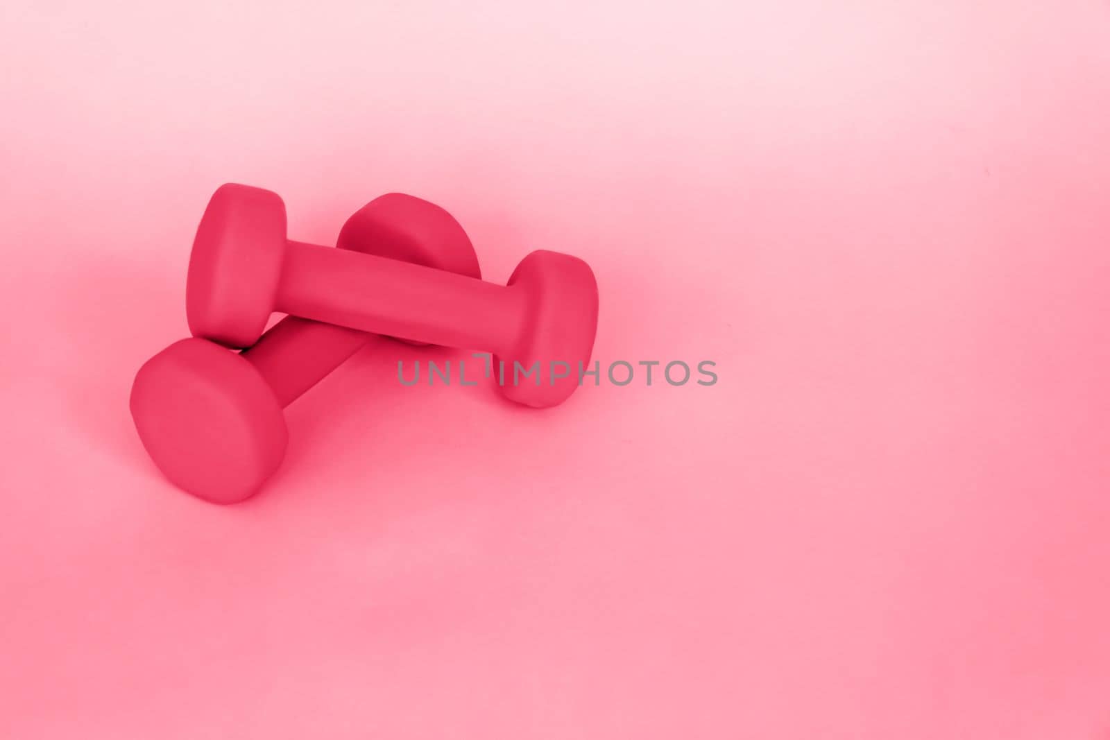 Green dumbbells for sports on a pink background. Sports, sports nutrition, healthy eating, diet. Space for the text. Viva Magenta Background color