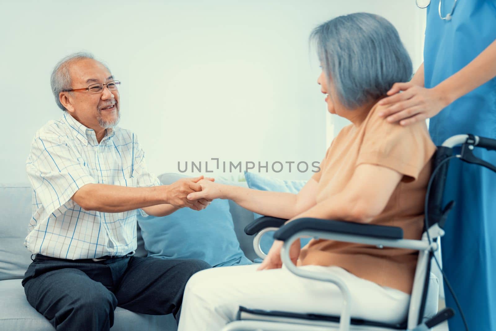 A contented senior couple and their in-home nurse. Elderly female in wheelchair with her young caregiver.