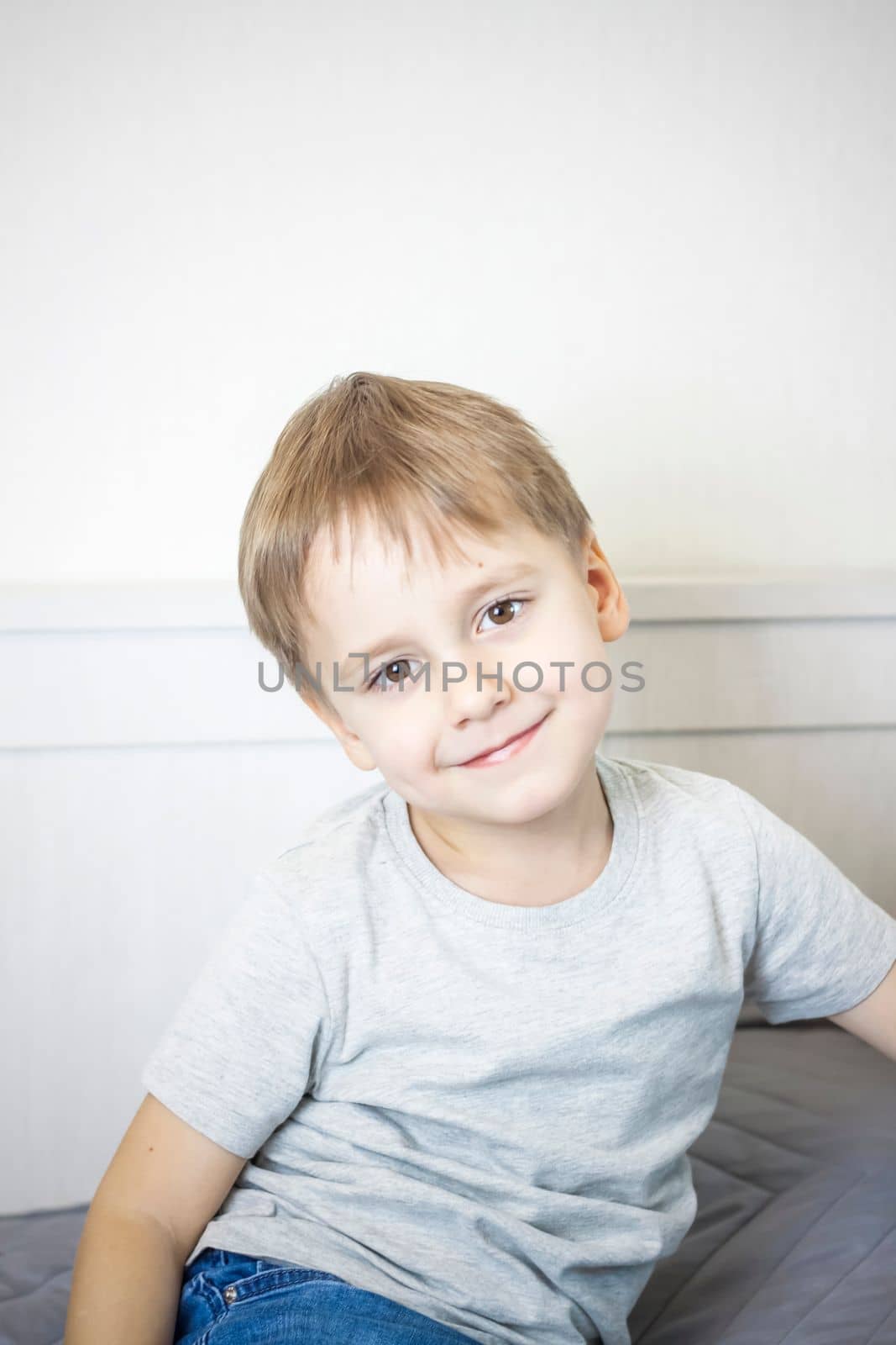 A photo of a handsome boy in a gray T-shirt looking at the camera. Portrait in a bright room. Natural, not staged photography. by Alina_Lebed