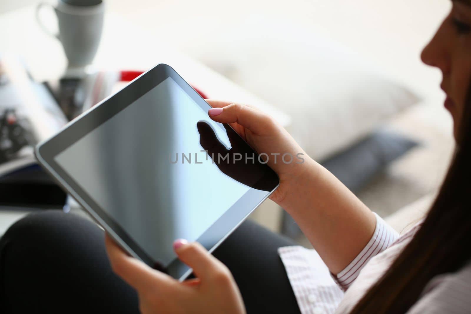 Female hands hold modern tablet at home. Mobile application developer or browsing information on the internet concept