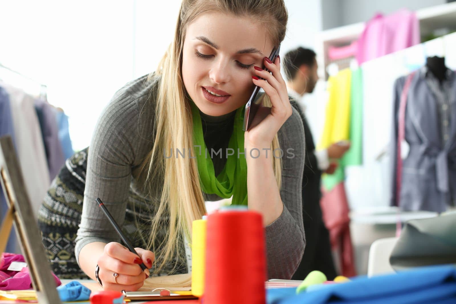 Woman designer stylist takes an order for tailoring by phone. Atelier services concept