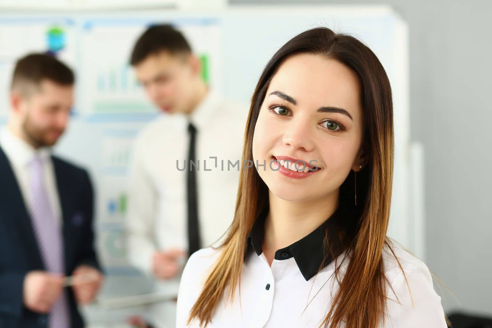 Successful business woman standing with employees in background in office. Successful business consultant concept