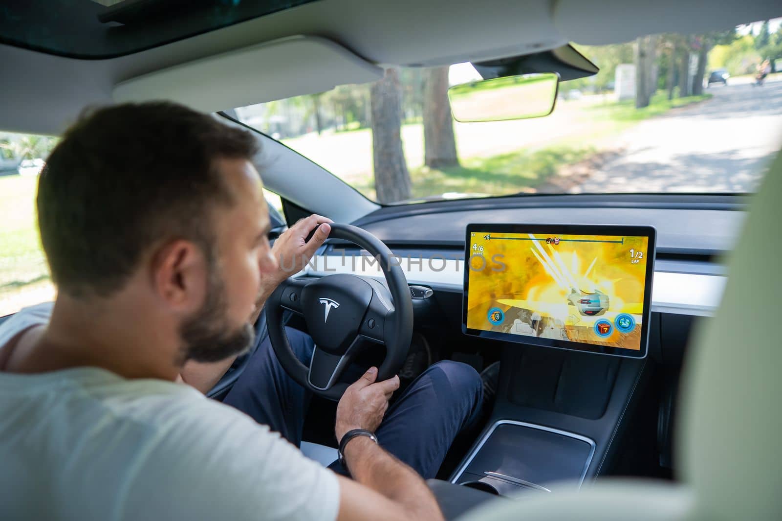 Novosibirsk, Russia - 10.08.2022: Caucasian man playing games while driving tesla car