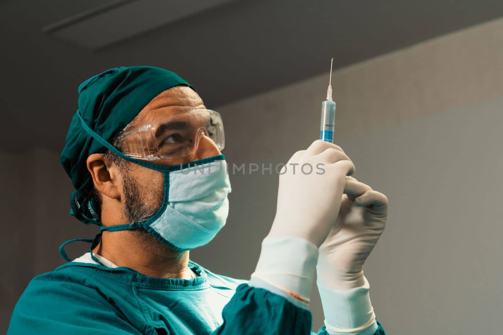 Surgeon fill syringe from medical vial for surgical procedure at sterile operation room. Doctor in full protective wear for surgery prepare anesthesia injection for his patient