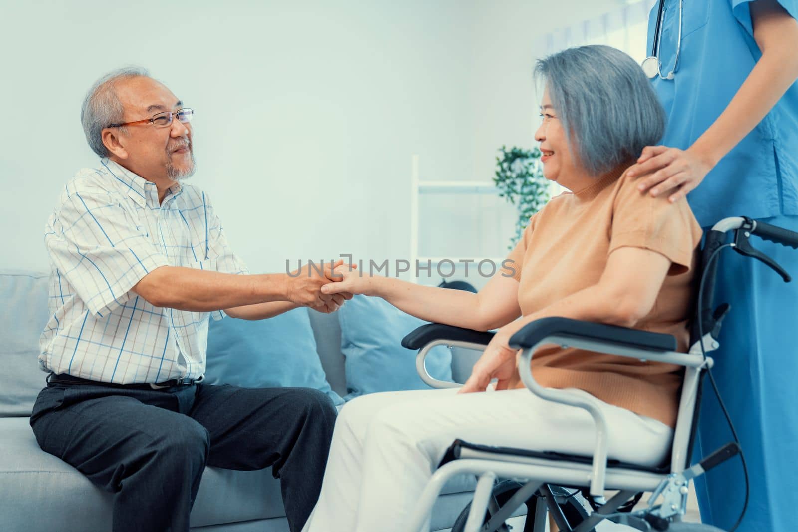 A contented senior couple and their in-home nurse. Elderly female in wheelchair with her young caregiver.