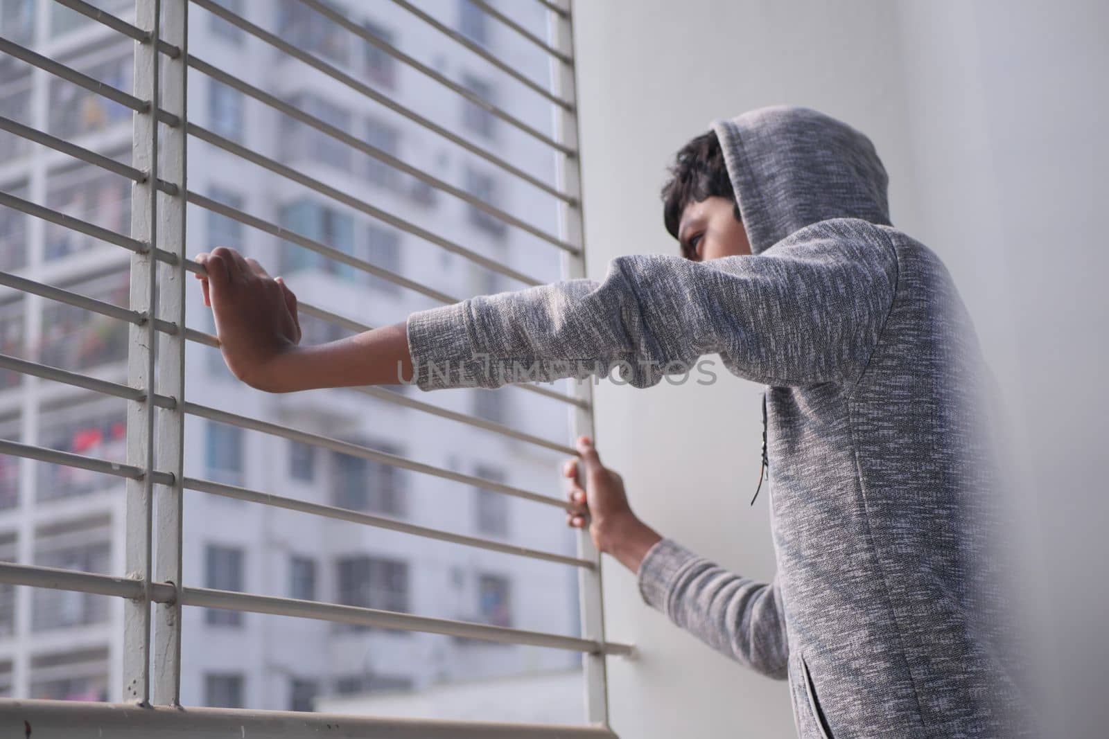 sad teenage boy looking through window .