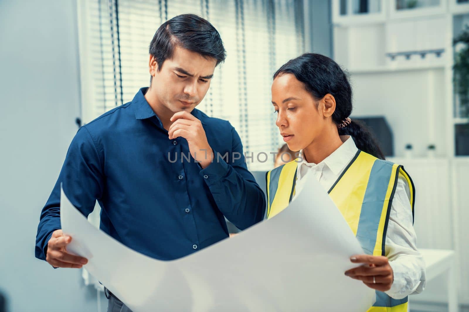 Competent investor investor discuss and brainstorm with engineer on blueprints, construction plans before putting them into action. Professional establishing investment plan for engineering projects.