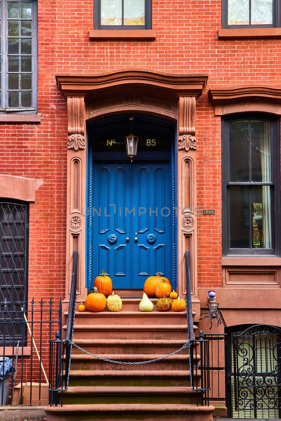 Image of Brick apartment building with steps to blue door and pumpkins straight on in New York City iconic Greenwich Village