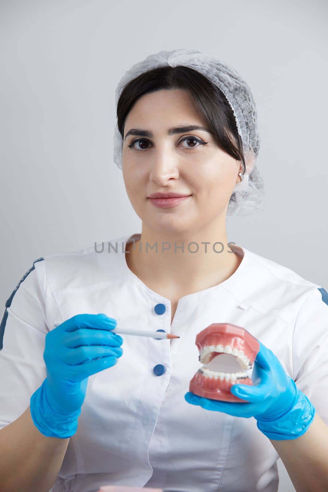 Orthodontist showing model of human jaw with wire braces and aligners explaining the difference by Mariakray